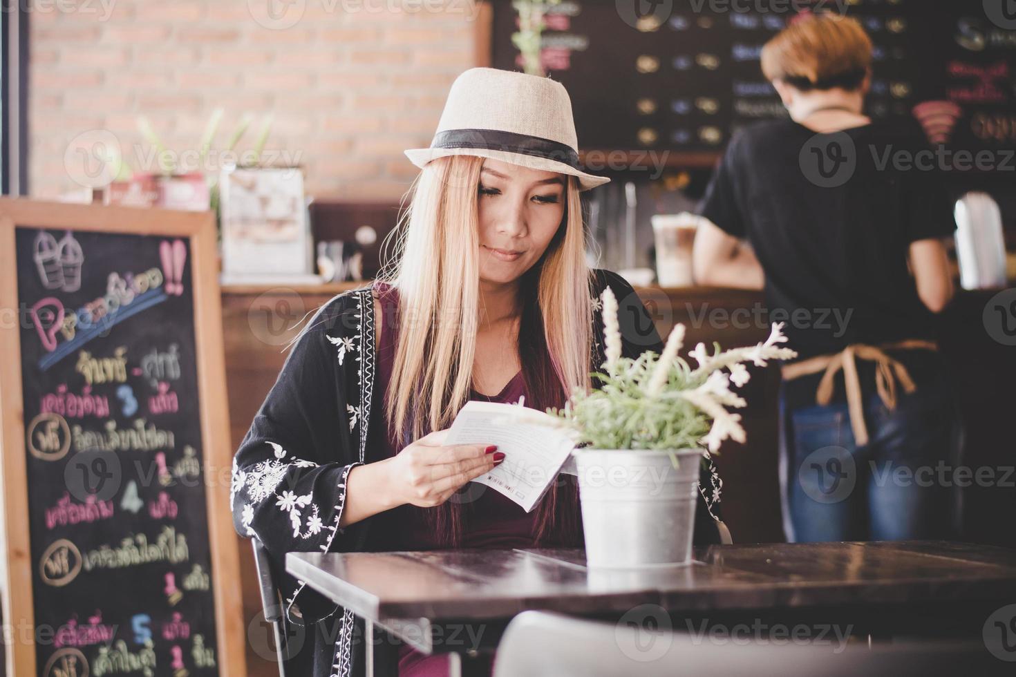 glückliche Geschäftsfrau, die Buch liest, während sie im Café entspannt foto