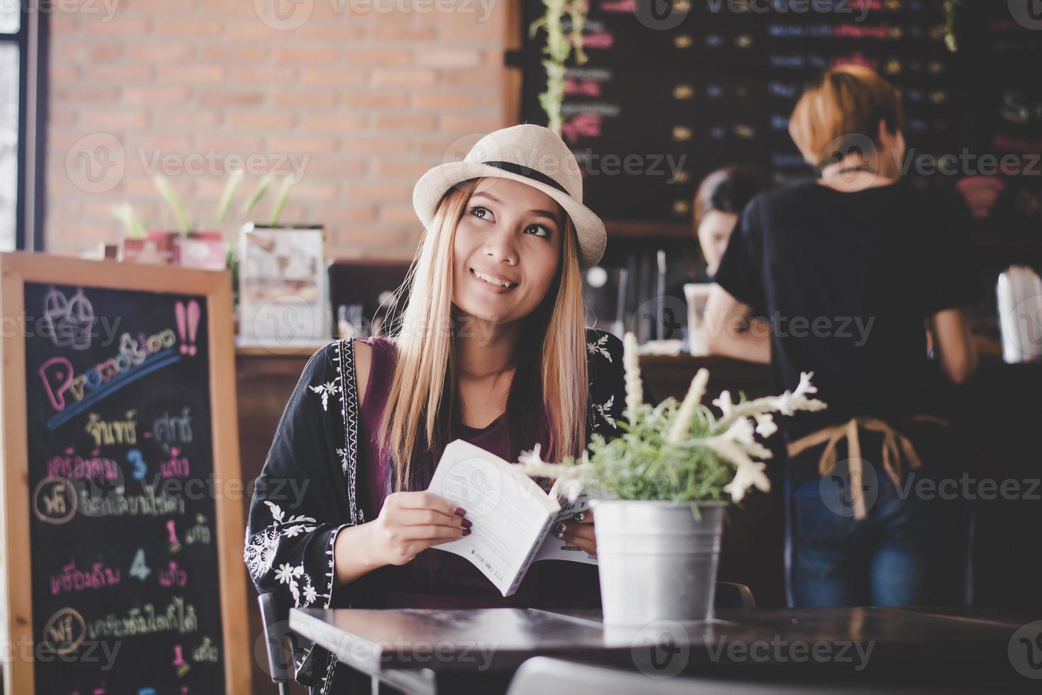 glückliche Geschäftsfrau, die Buch liest, während sie im Café entspannt foto