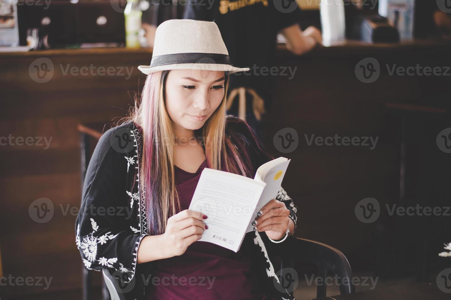 glückliche Geschäftsfrau, die Buch liest, während sie im Café entspannt foto