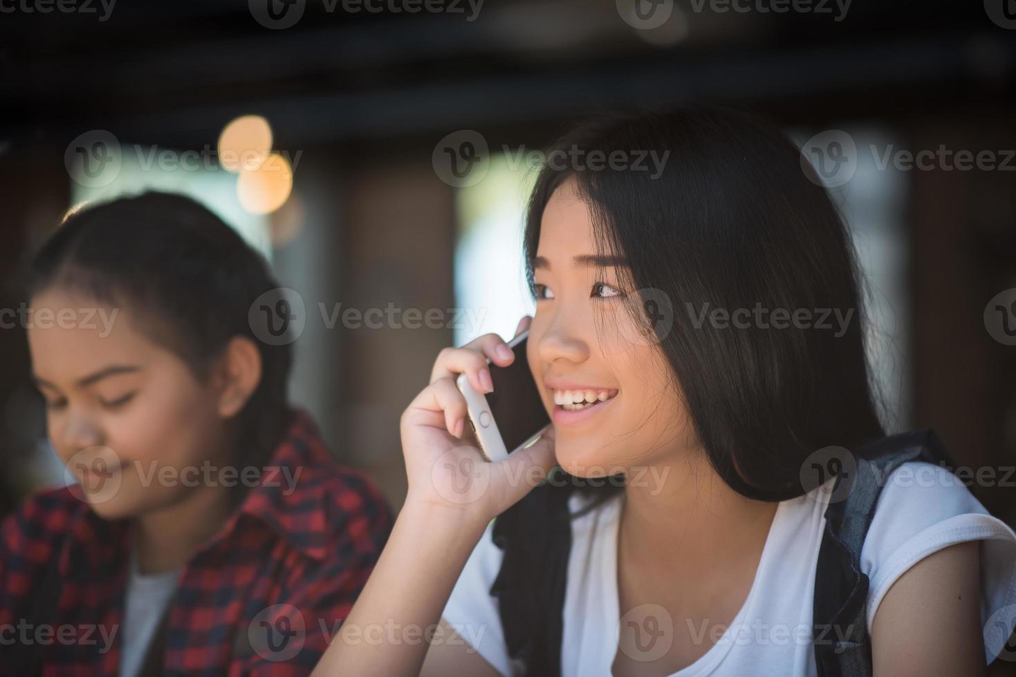 junge Frauen, die Smartphone am Fenstercafé benutzen und betrachten foto