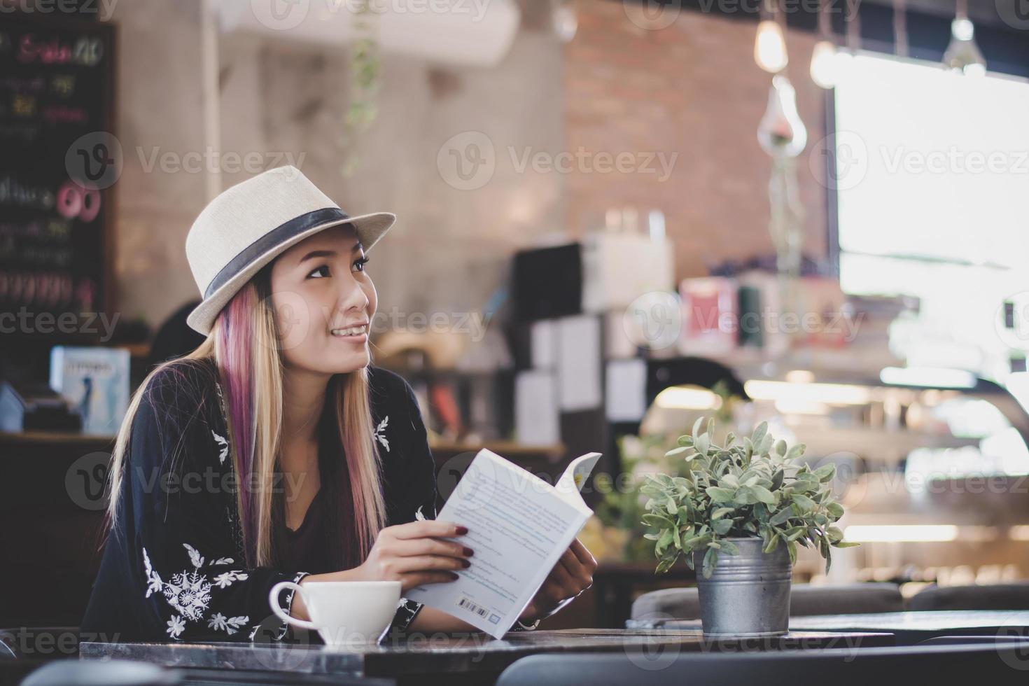 glückliche Geschäftsfrau, die Buch liest, während sie im Café entspannt foto