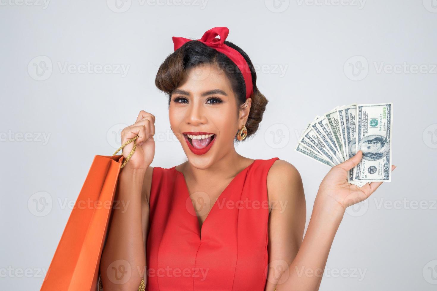 schöne asiatische Frau, die farbige Einkaufstaschen und Geld hält foto