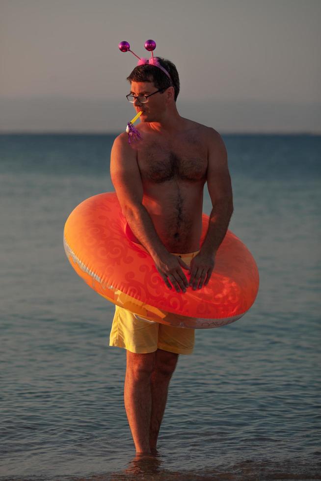 Mann mit Partydekor am Strand foto