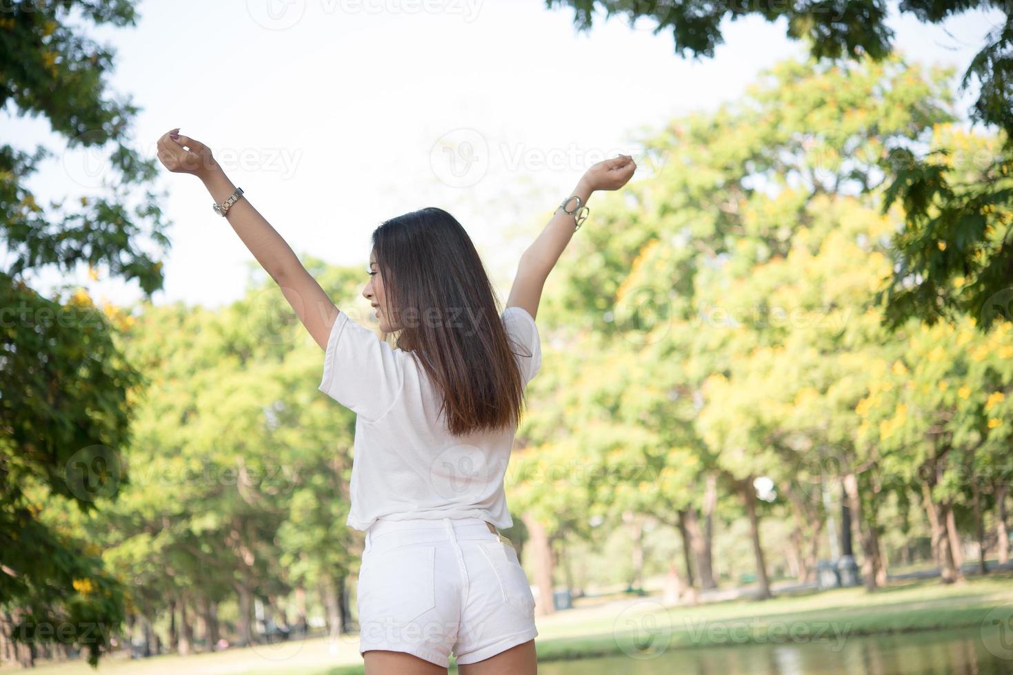 Porträt eines Mädchens, das Arme hebt und im Park lacht foto