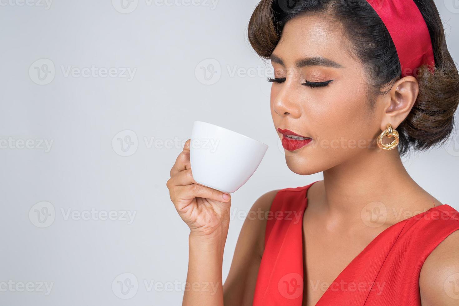 glückliche modische Frau, die eine Kaffeetasse hält foto