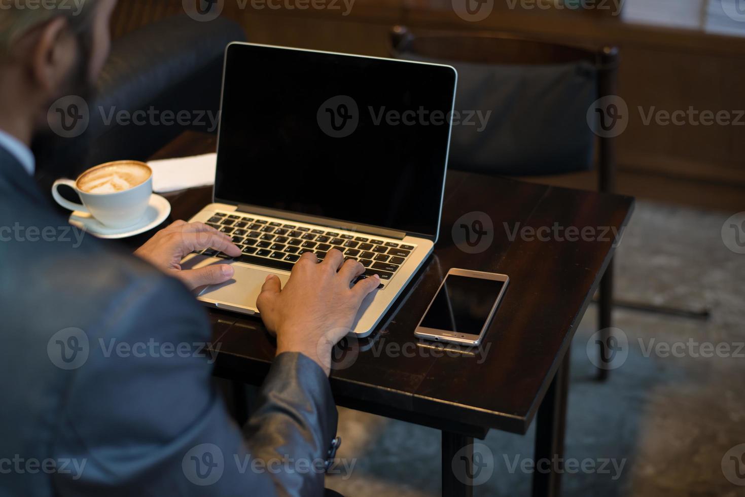 Geschäftsmann, der auf Laptop-Tastatur am Arbeitsplatz tippt foto