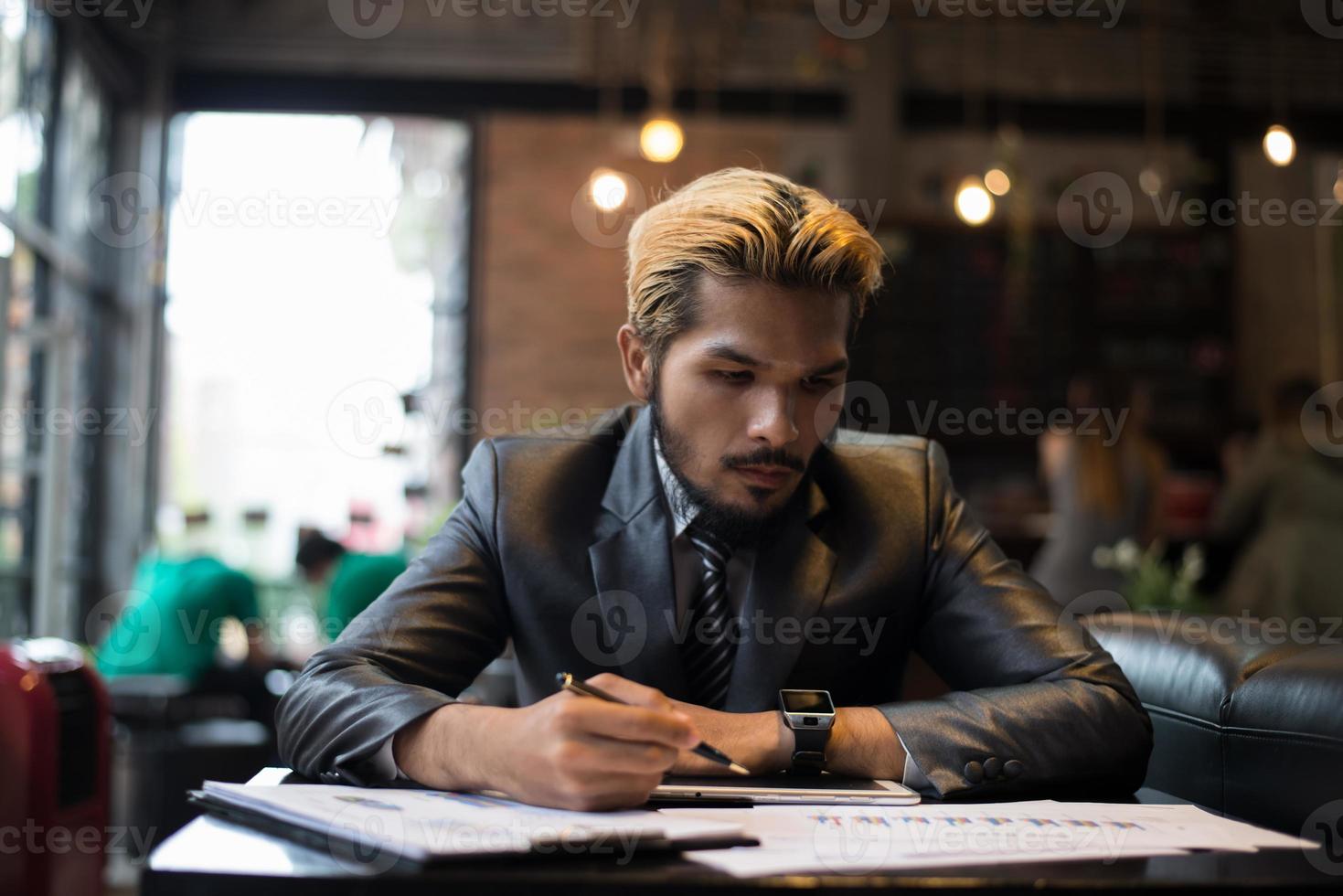 schöner Geschäftsmann, der auf Notizbuch mit Tasse Kaffee im Restaurant schreibt foto