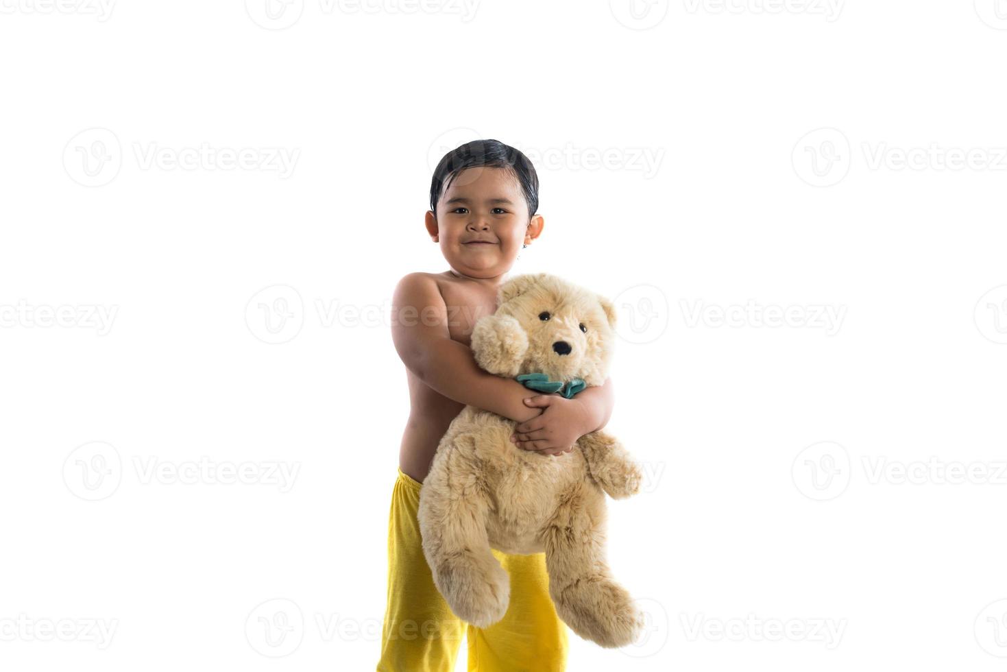 kleiner asiatischer Junge, der einen großen Teddybär lokalisiert auf weißem Hintergrund hält foto