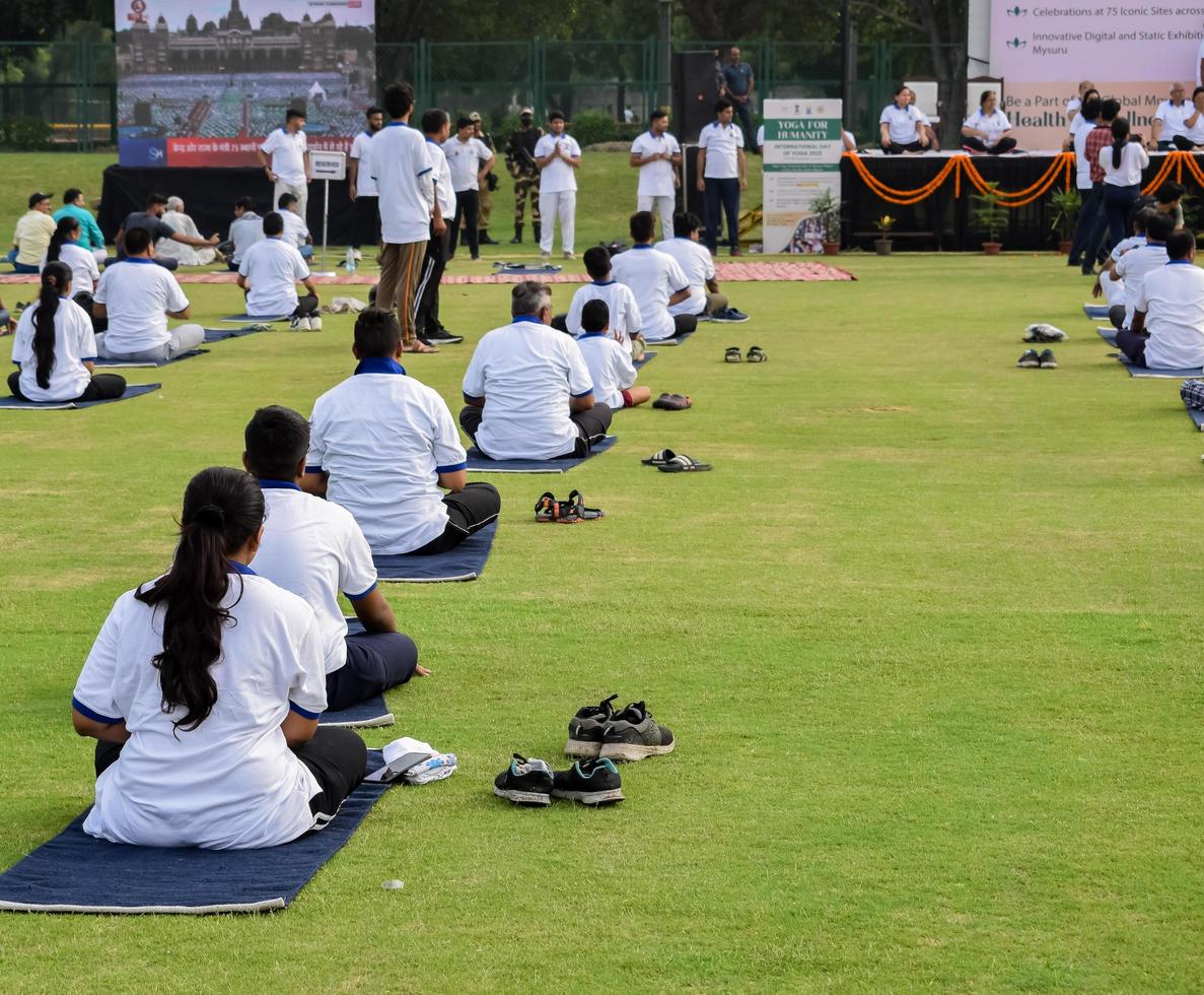 neu-delhi, indien, 21. juni 2022 - gruppen-yoga-übungssitzung für menschen im yamuna-sportkomplex in delhi am internationalen yoga-tag, große gruppe von erwachsenen, die an yoga-kursen im cricket-stadion teilnehmen foto