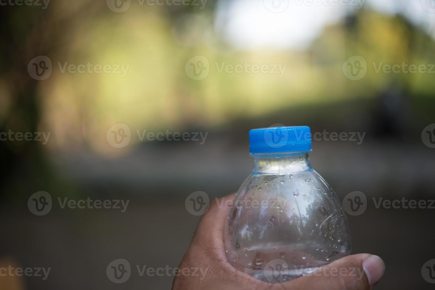 Wasserflasche mit unscharfem Naturhintergrund und Kopienraum foto