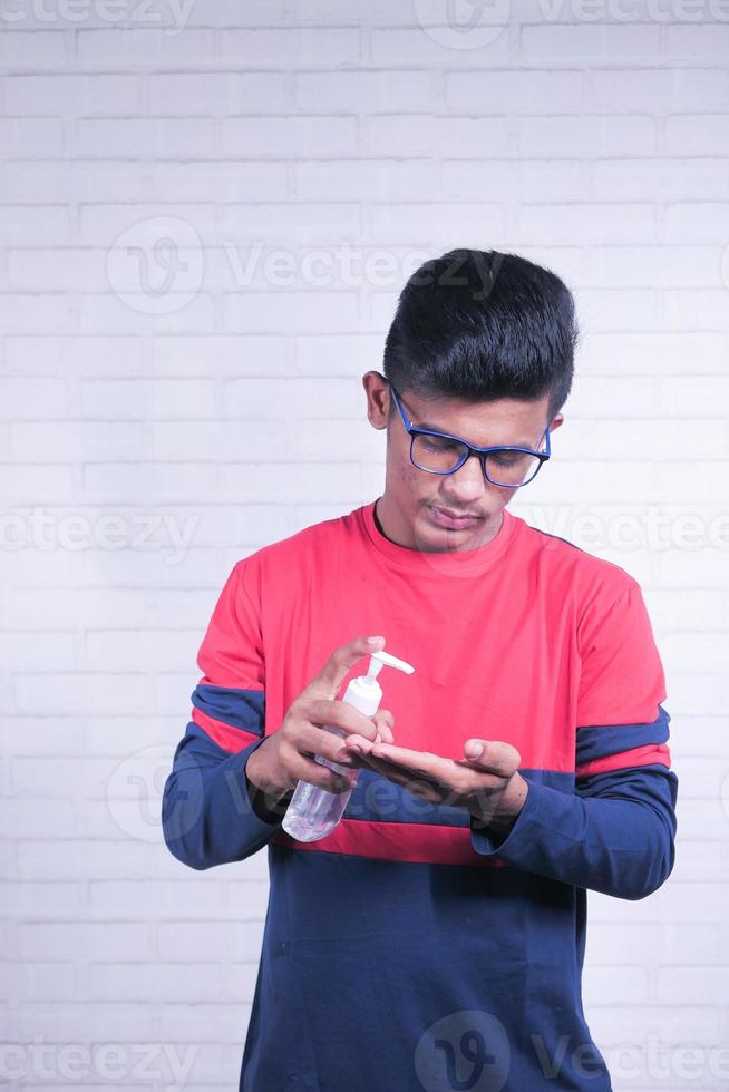 junger asiatischer Mann, der Desinfektionsflüssigkeit zur Verhinderung des Koronavirus verwendet foto