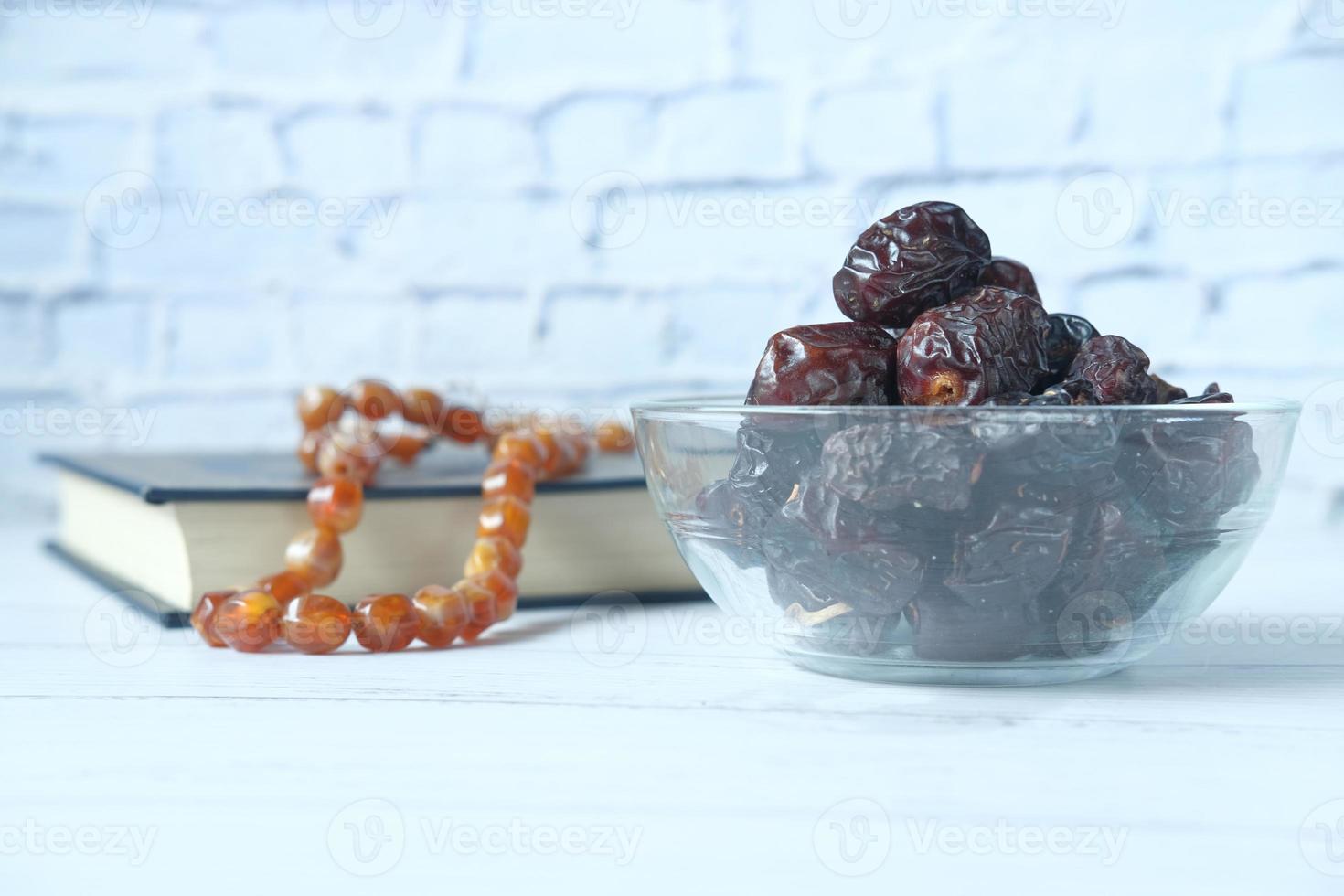 frische Dattelfrüchte in einer Schüssel und heiliges Buch des Korans auf dem Tisch foto