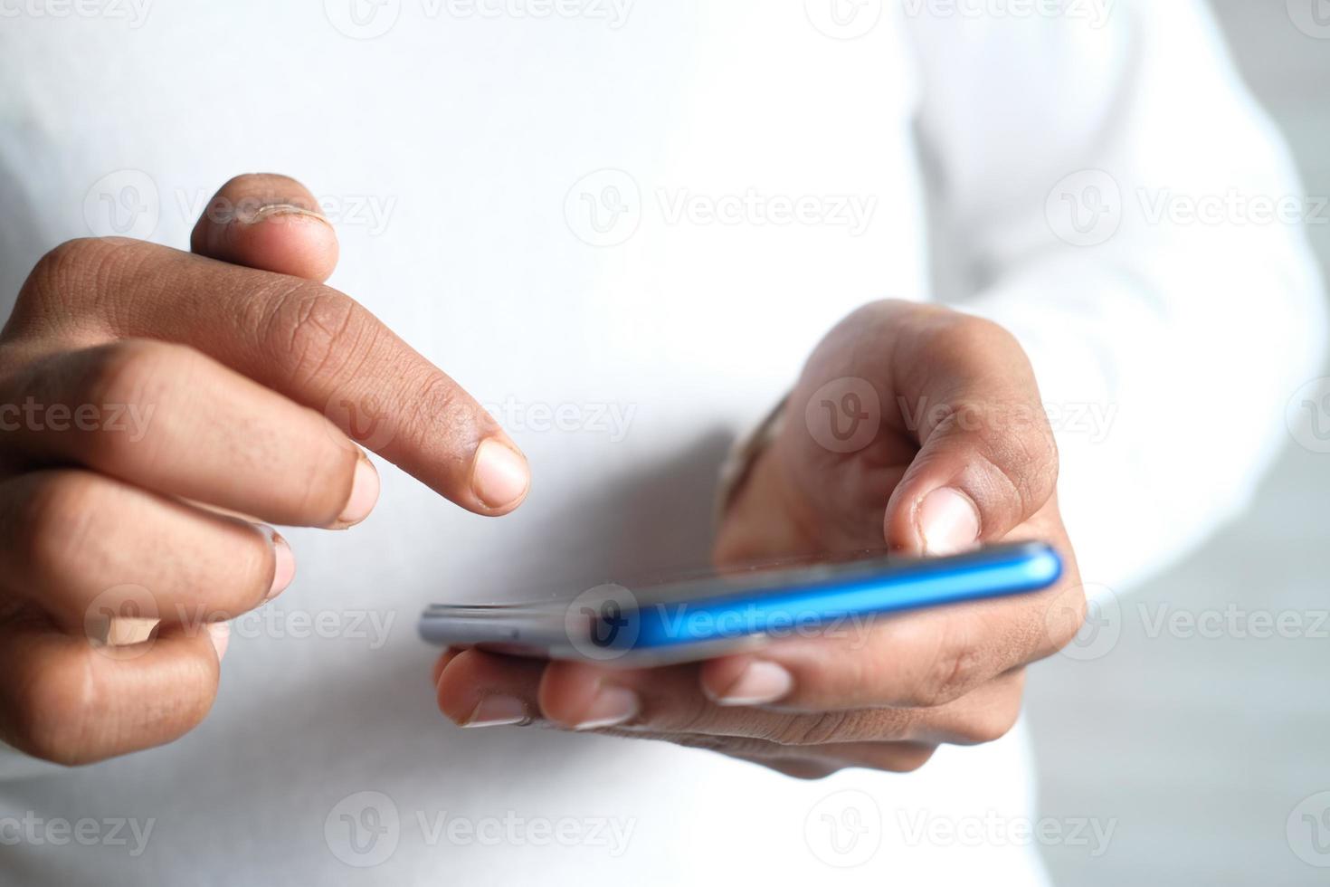 Nahaufnahme der Hand des jungen Mannes unter Verwendung eines blauen Smartphones foto