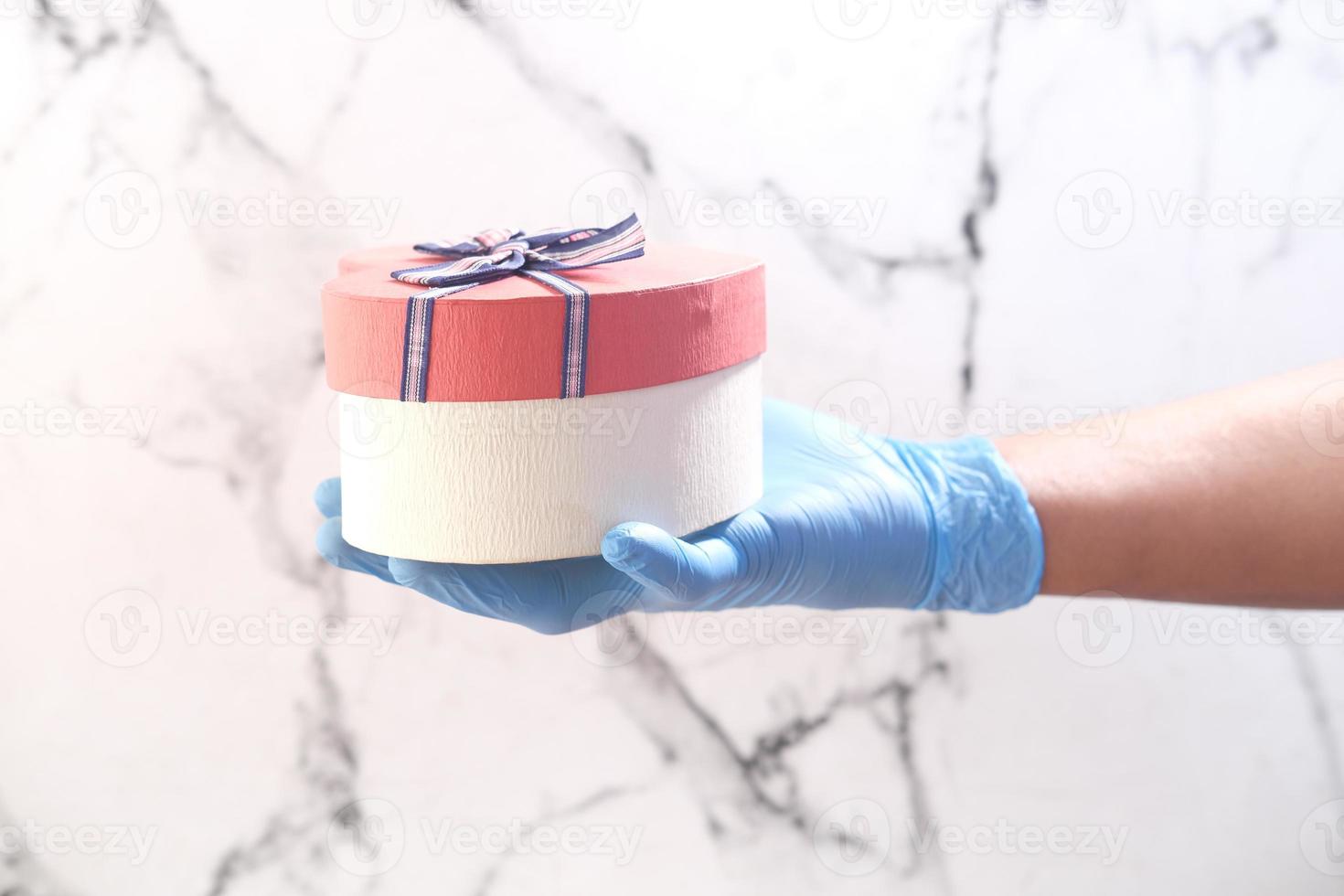 männliche Hand in einem blauen medizinischen Handschuh gibt ein Geschenk foto