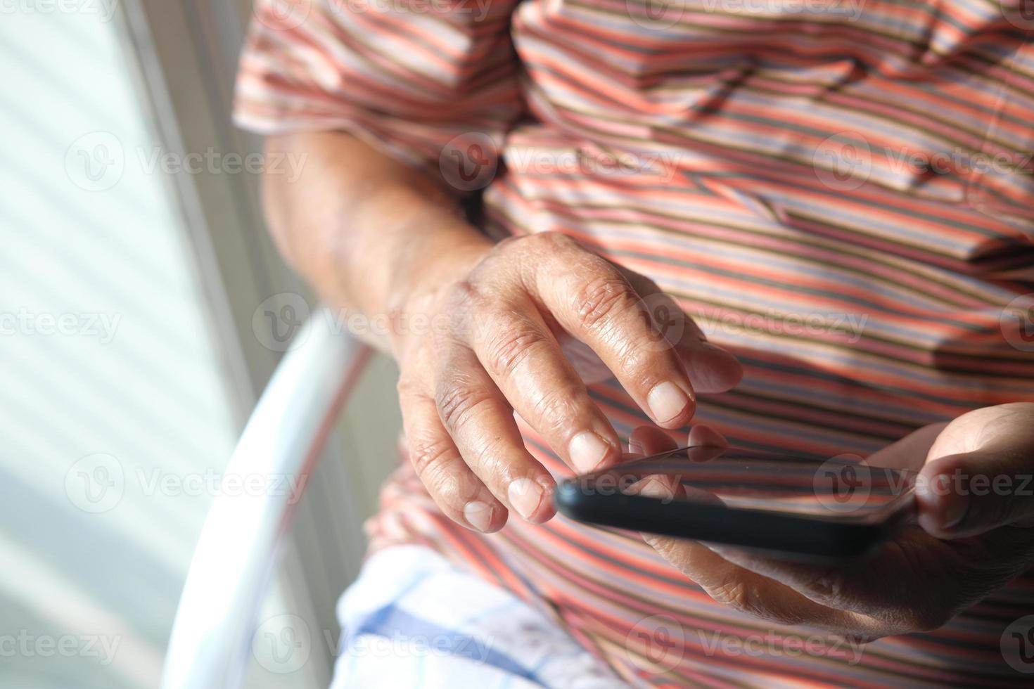 Nahaufnahme eines älteren Mannes, der ein Smartphone zu Hause benutzt foto