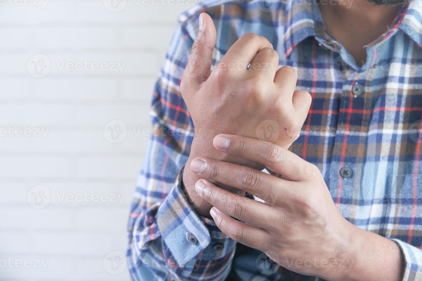 Mann, der sein Handgelenk hält und Schmerzen in der Hand mit Kopierraum leidet foto