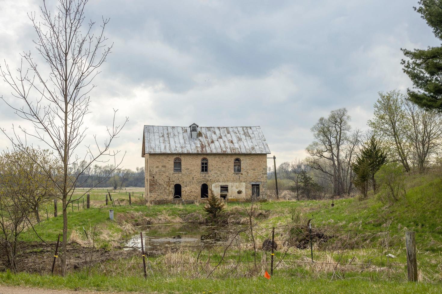 altes Steinhaus auf grünem Hügel unter bewölktem Himmel foto