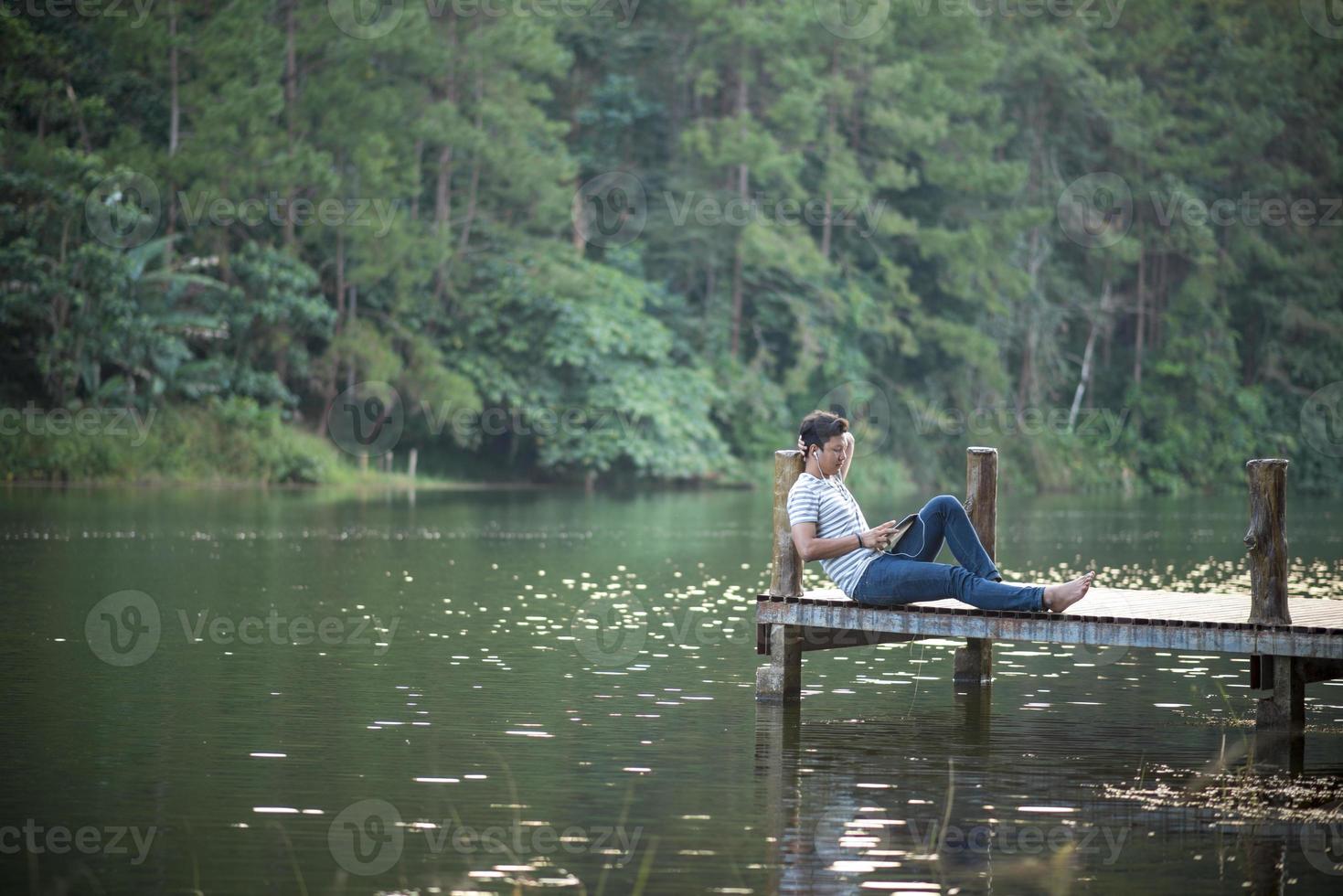 einzelner Mann, der Musik auf einem Dock hört foto