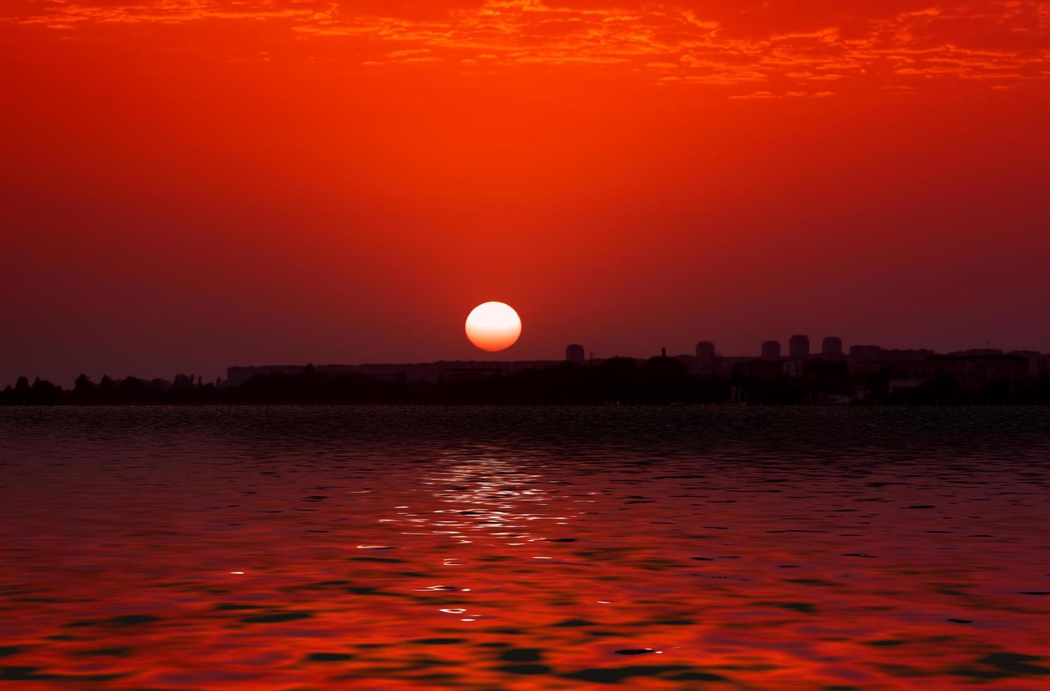 Sonnenuntergang über der Skyline der Stadt durch Gewässer foto
