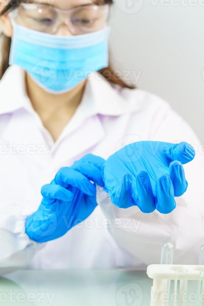 Wissenschaftlerhände, die nitrilblaue Latexhandschuhe in Laborkittel mit Nitrilhandschuhen einlegen foto