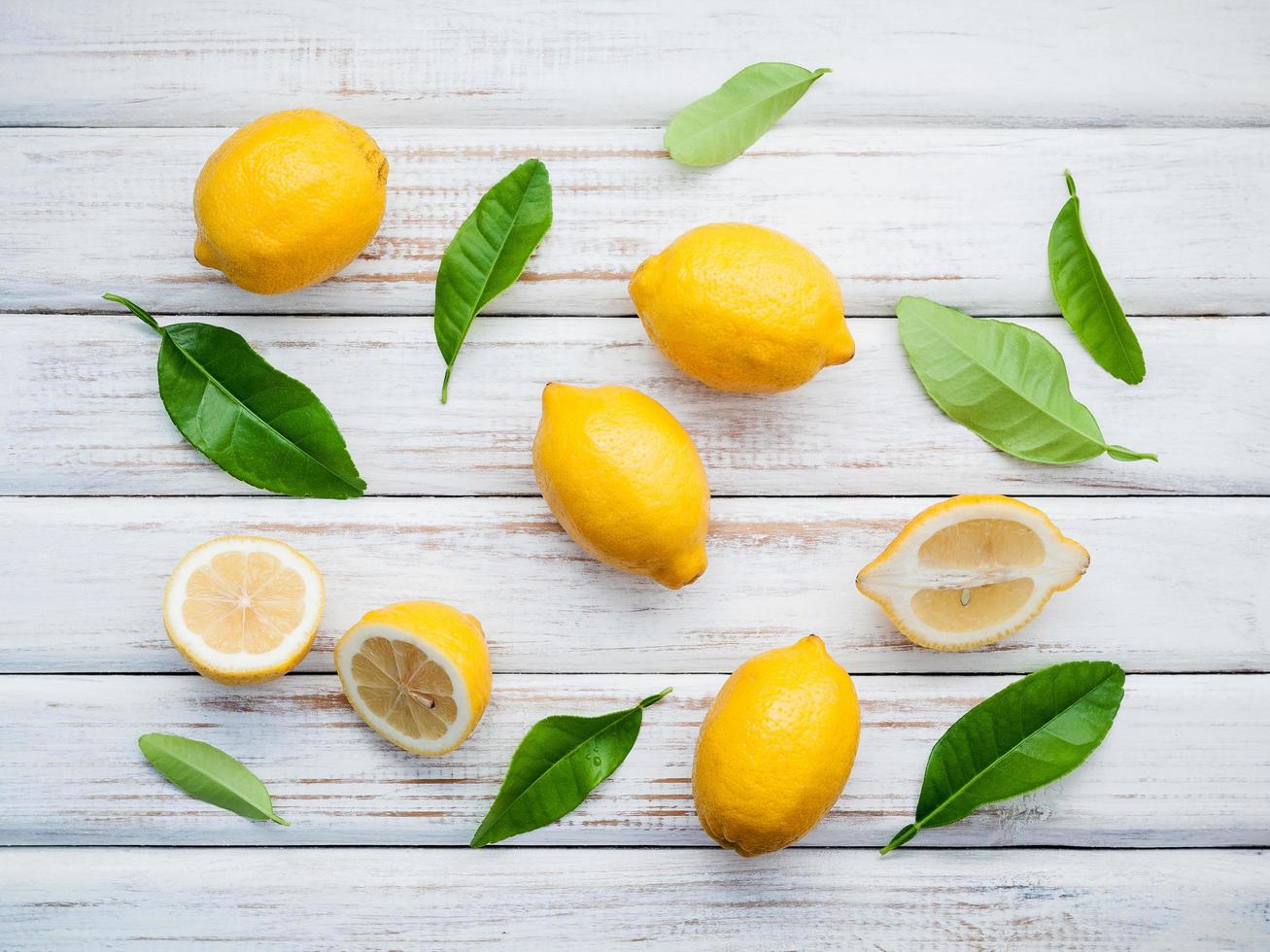 frische Zitronen und Zitronenblätter auf rustikalem hölzernem Hintergrund foto