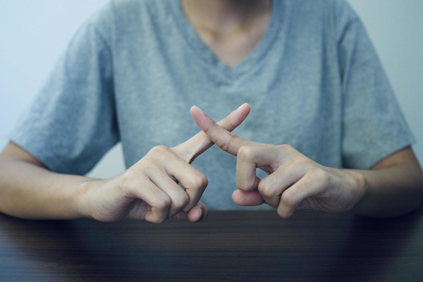 Geschäftsfrau Kreuzung beide Index Finger tragen ein grau T-Shirt, besorgt ernst zögerte zwischen zwei Kopieren Räume. Geschäft Idee. foto