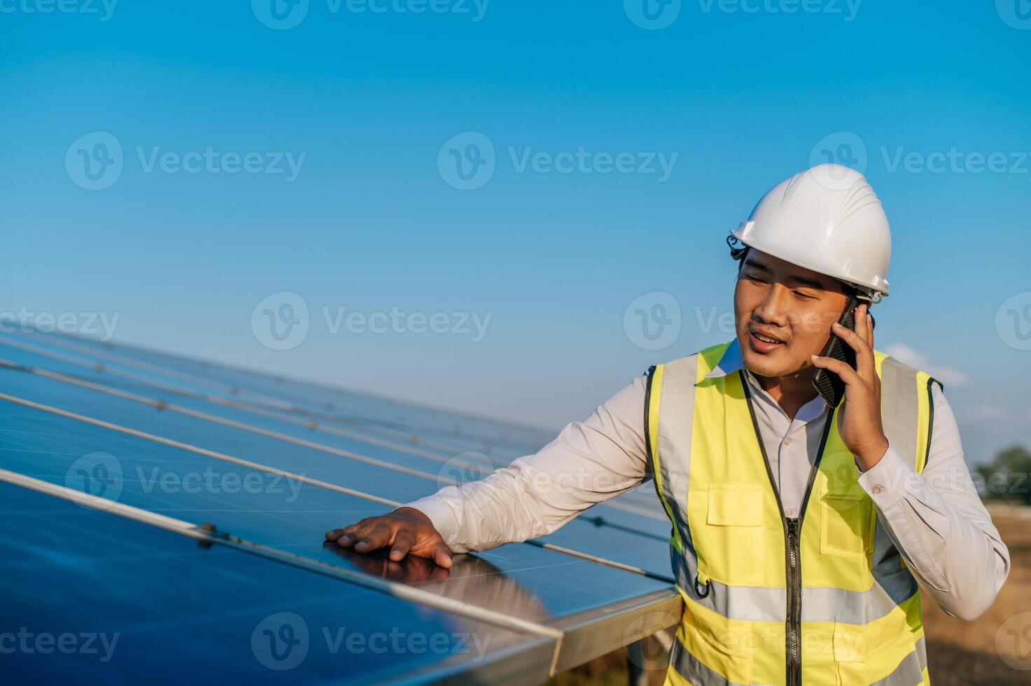 Junger Ingenieur nutzt Smartphone, während er im Solarpark arbeitet foto