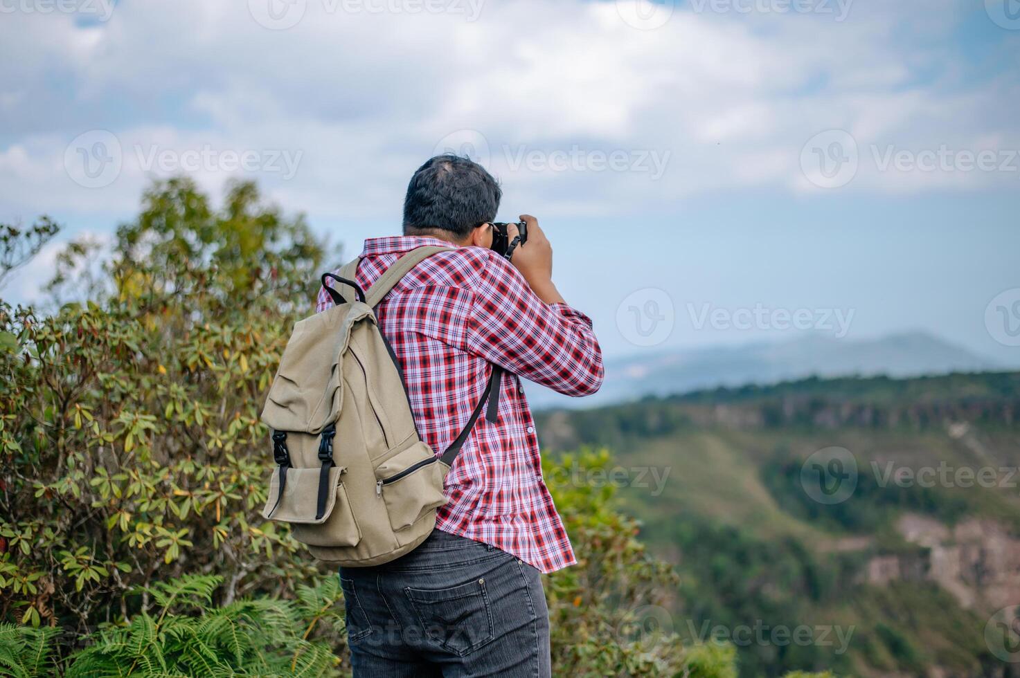junger Rucksacktourist benutzt Kamera, um Bilder im Wald zu machen. foto