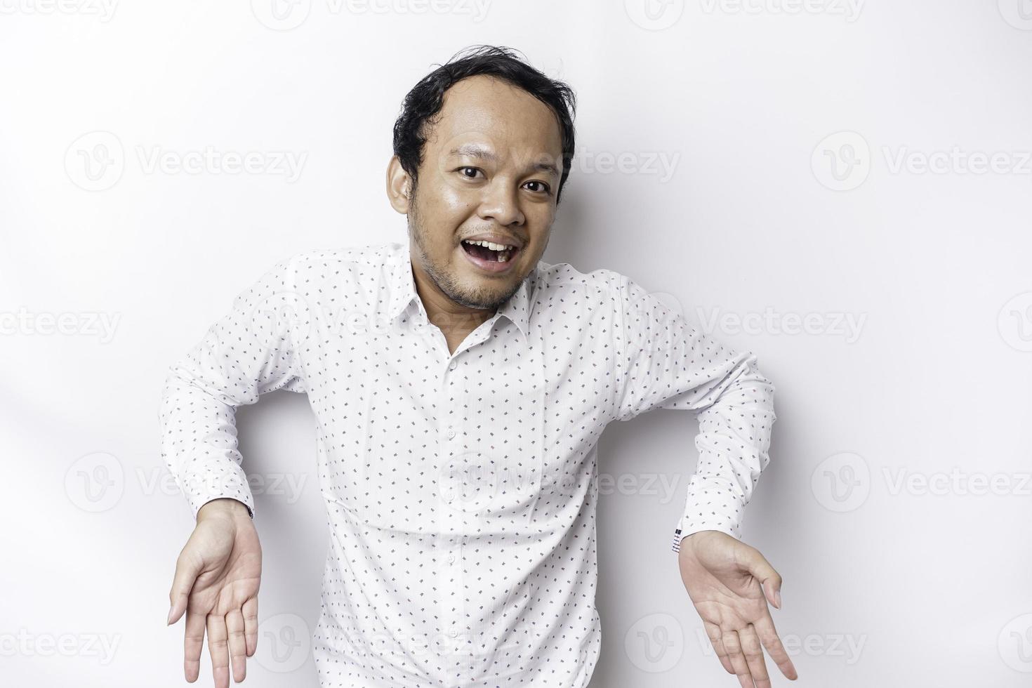 aufgeregt asiatisch Mann tragen Weiß Hemd zeigen beim das Kopieren Raum unten ihn, isoliert durch Weiß Hintergrund foto