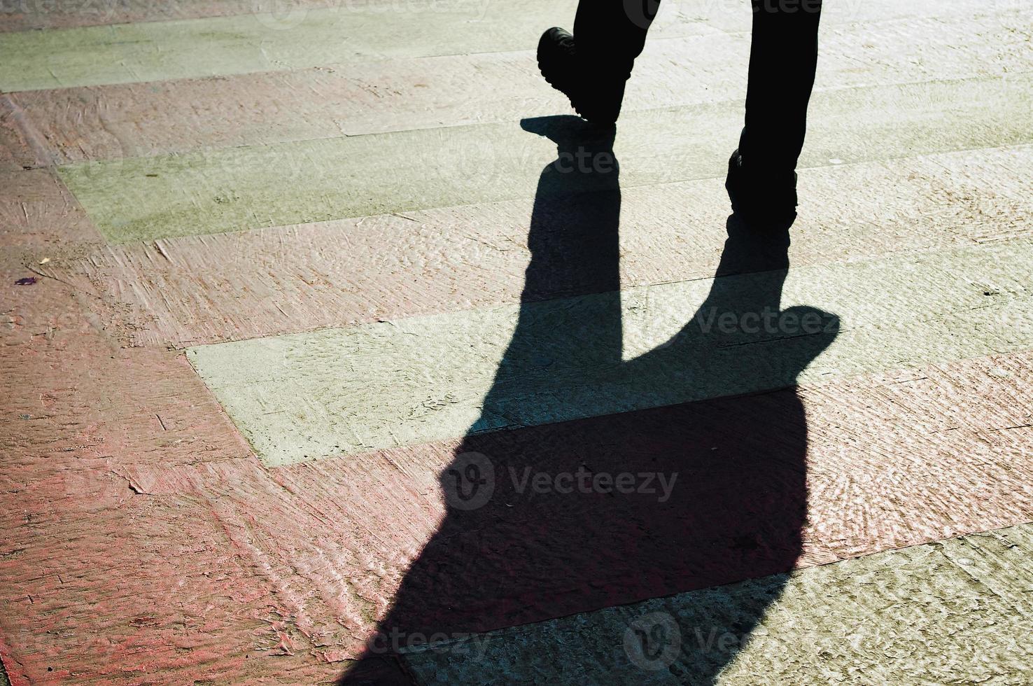 Fußgänger Gehen auf Zebra Kreuzung werfen schwer schwarz Schatten Oh das Straße. foto