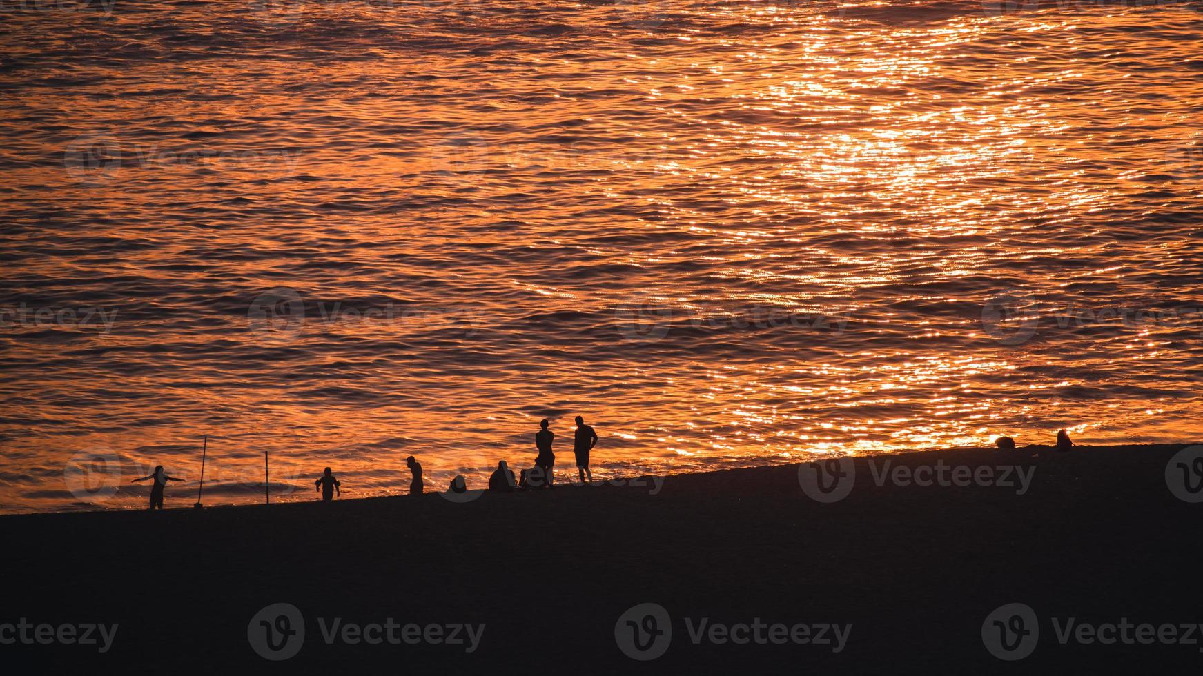 Menschen am Strand während des Sonnenuntergangs foto