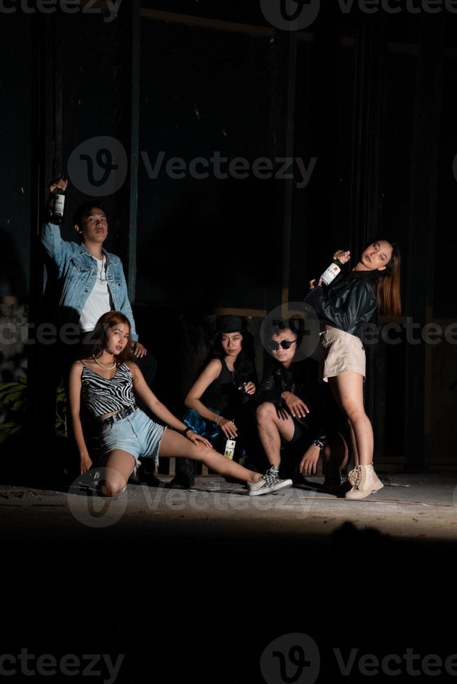 ein Gruppe von Jugendliche im schrullig Kleider posieren zusammen wie freunde im ein Disko Bar mit ein sehr cool Ausdruck foto