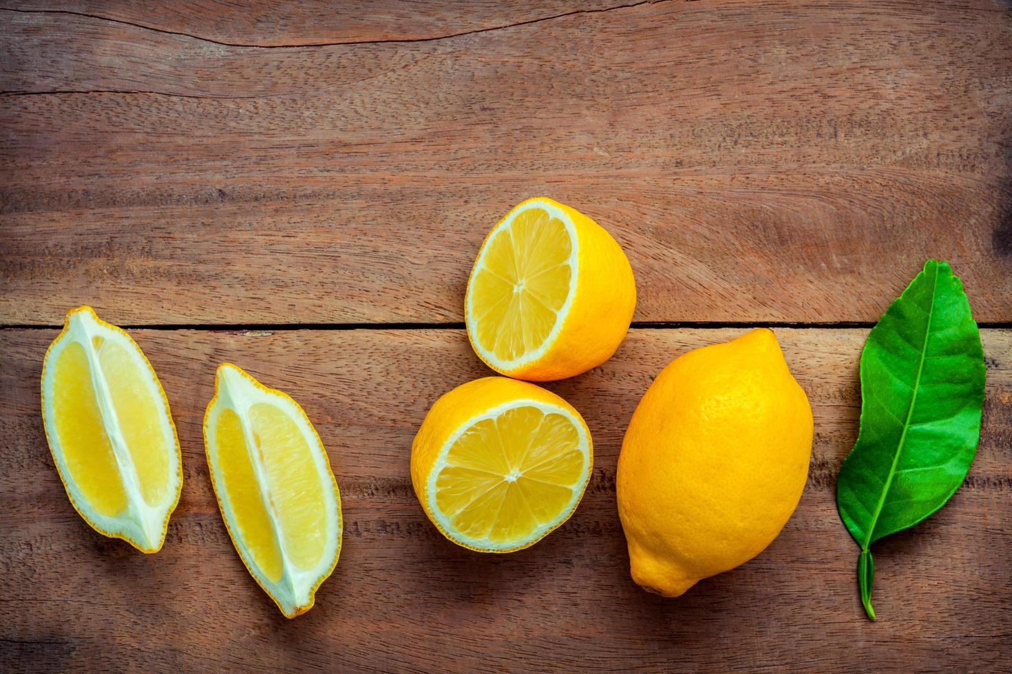 frische Zitronen und Blätter auf einem hölzernen Hintergrund foto