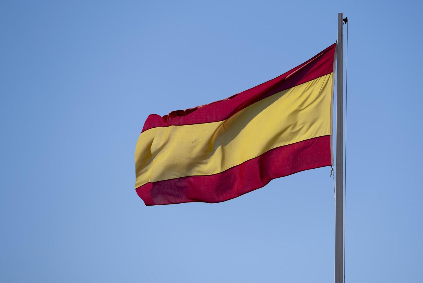spanische Flagge auf einem Mast, der im Wind fliegt foto