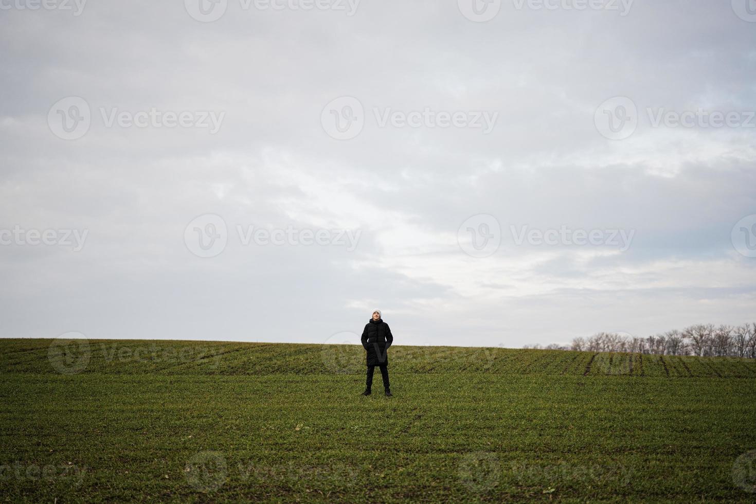 Teen Junge tragen schwarz Jacke und Weiß Hut außen, genießt im das früh Frühling Feld.. foto