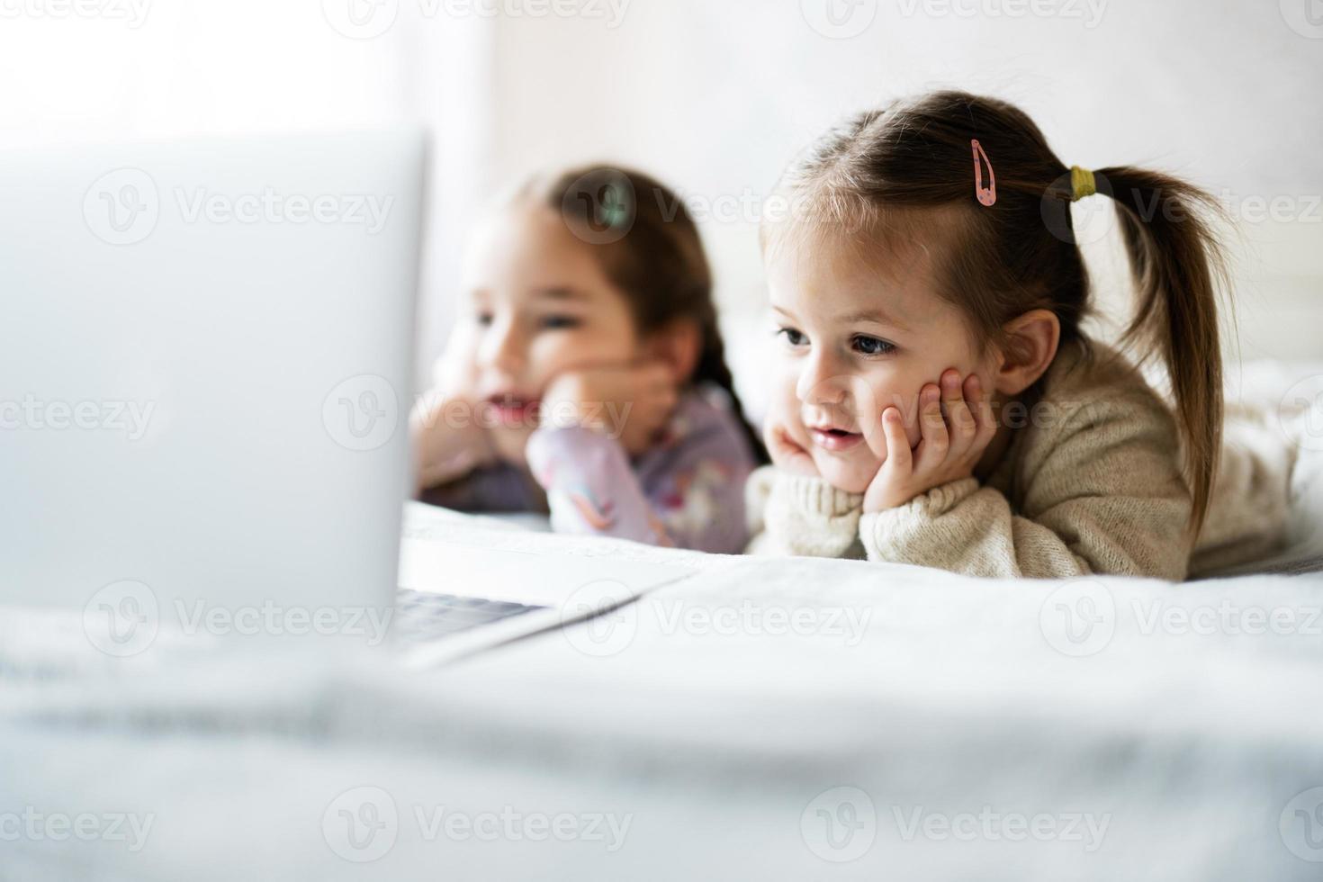 zwei Mädchen Schwestern Aufpassen auf Laptop. Technologie und Zuhause Konzept. foto