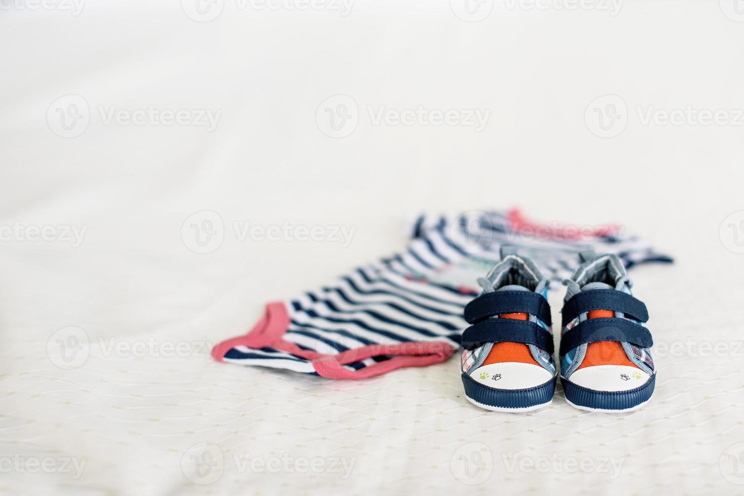 Kinder- Blau Turnschuhe im Damen Hände auf das Hintergrund von Decken und Kinder- Kleider foto