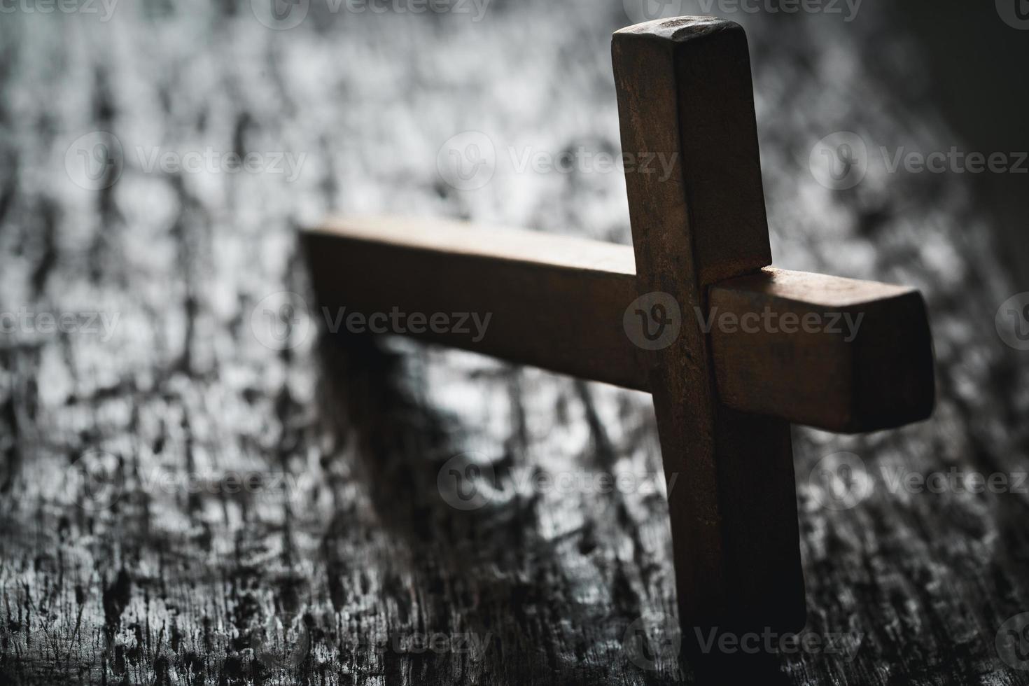 ein hölzern Christian Kreuz Kruzifix auf ein Grunge Tafel Hintergrund. hölzern Christian Kreuz auf grau Tabelle gegen verschwommen Beleuchtung, Raum zum Text. foto