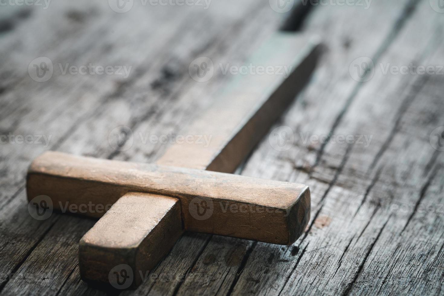 ein hölzern Christian Kreuz Kruzifix auf ein Grunge Tafel Hintergrund. hölzern Christian Kreuz auf grau Tabelle gegen verschwommen Beleuchtung, Raum zum Text. foto