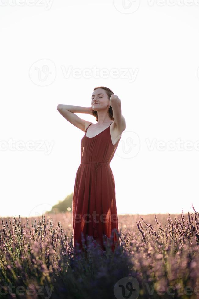 ein rothaarig jung Mädchen ohne bilden ist ruhen im ein Lavendel Feld. Sommer- Ferien und Reise Zeit. foto