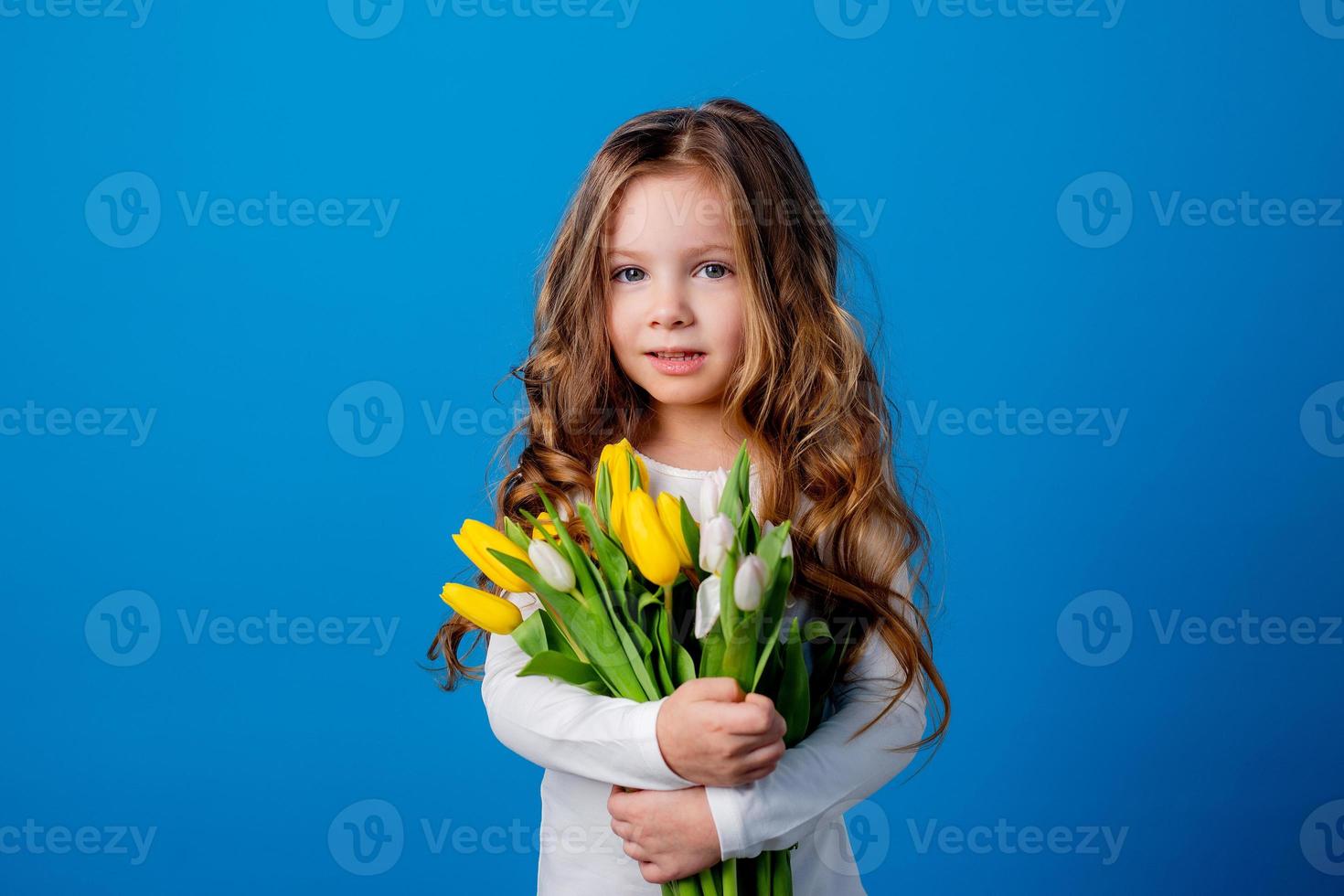 Porträt von ein charmant lächelnd wenig Mädchen mit ein Strauß von Tulpen im ihr Hände. Lebensstil. frisch Blumen. International Damen Tag. Raum zum Text. hoch Qualität Foto