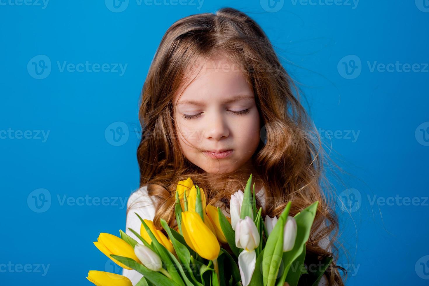 Porträt von ein charmant lächelnd wenig Mädchen mit ein Strauß von Tulpen im ihr Hände. Lebensstil. frisch Blumen. International Damen Tag. Raum zum Text. hoch Qualität Foto