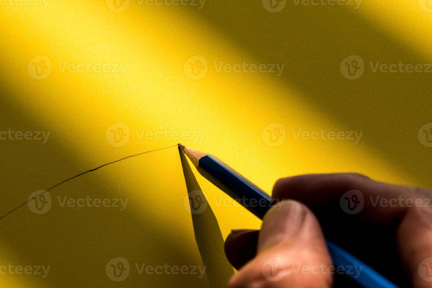 die Hand des Menschen, die einen Bleistift hält, um im Schatten auf das Papier zu schreiben foto