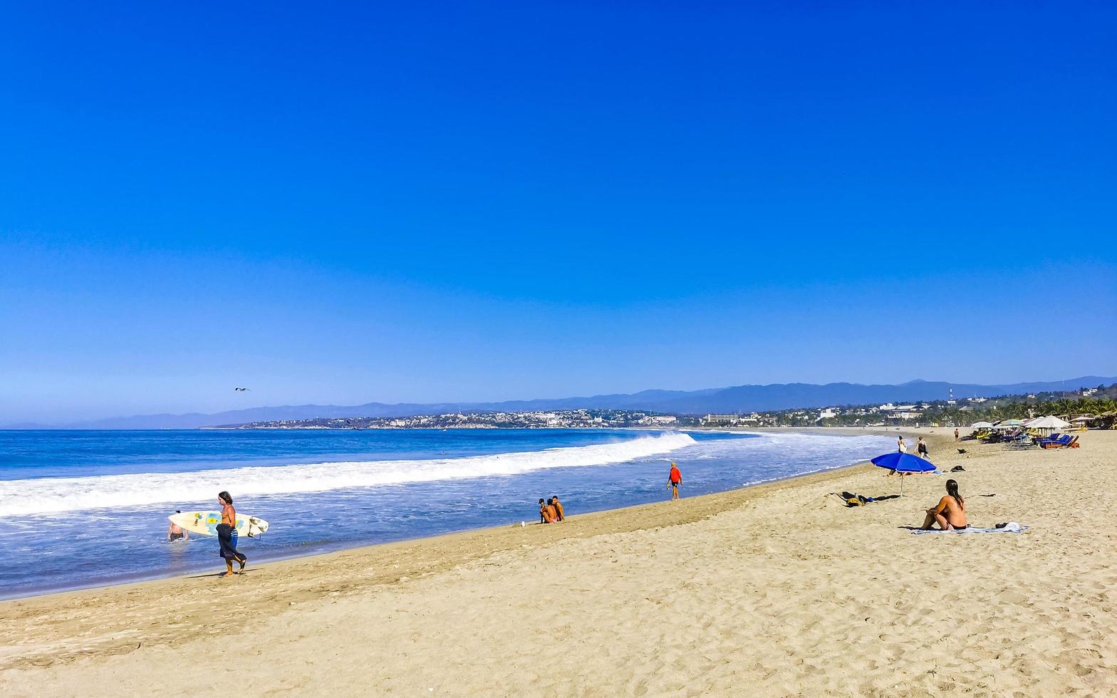 puerto escondido Oaxaca Mexiko 2023 Menschen Sonnenschirme Sonne Liegen Strand Wellen Palmen Zikatela Mexiko. foto