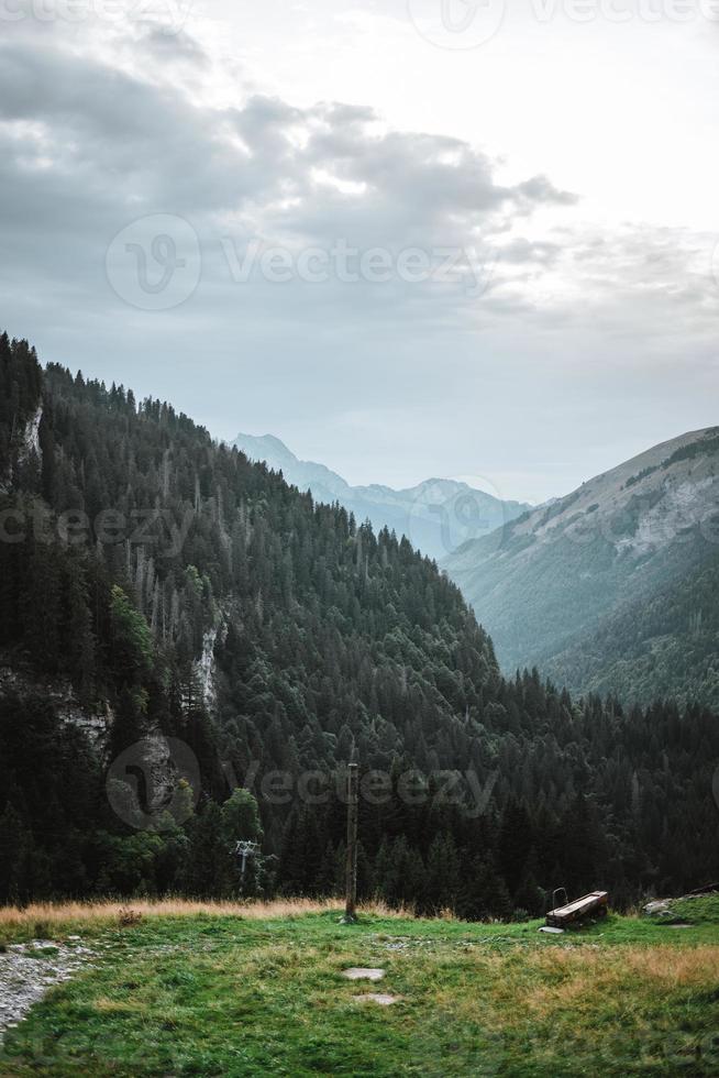 majestätisch Berge im das Alpen bedeckt mit Bäume und Wolken foto