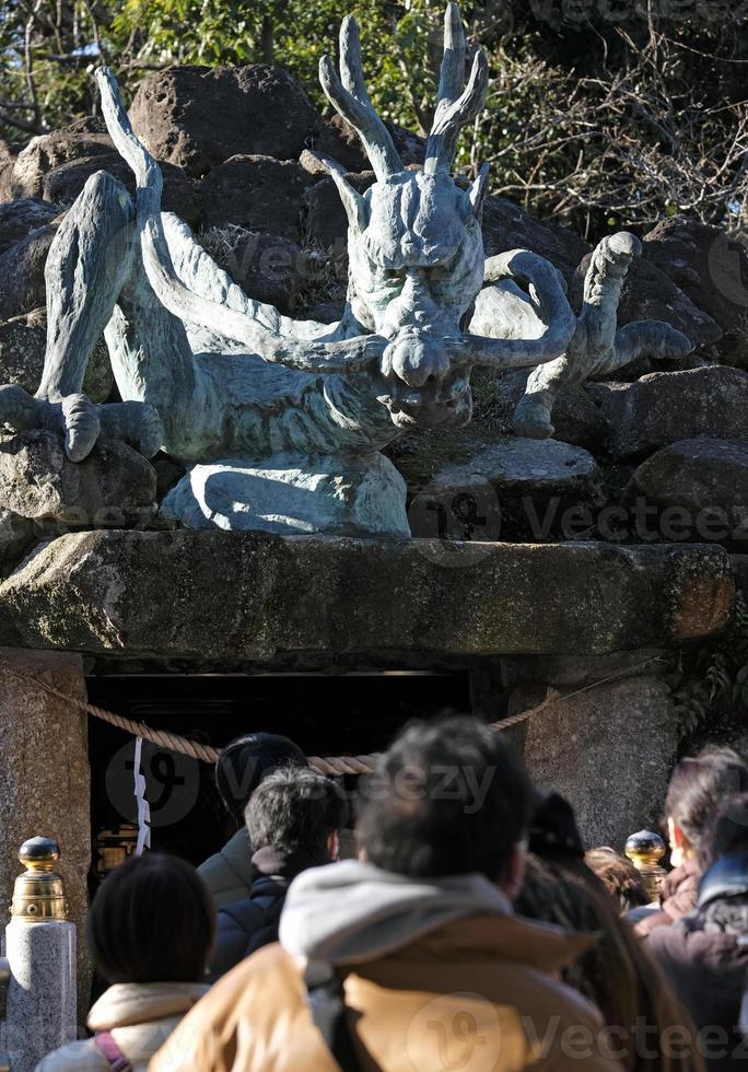 Drachen Statue beim Drachen Palast, Teil von Enoshima Schrein auf Enoshima Halbinsel mit anonym Menschen gesehen von das zurück auf ein sonnig Tag foto