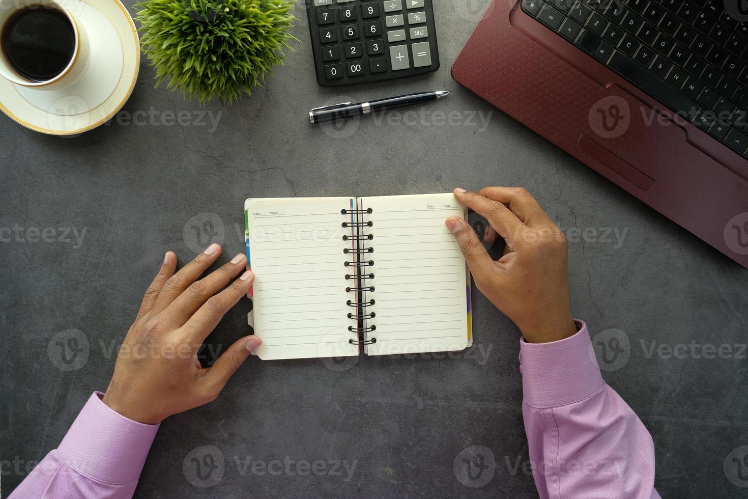 Mann blätterte durch ein Notizbuch auf dem Schreibtisch foto