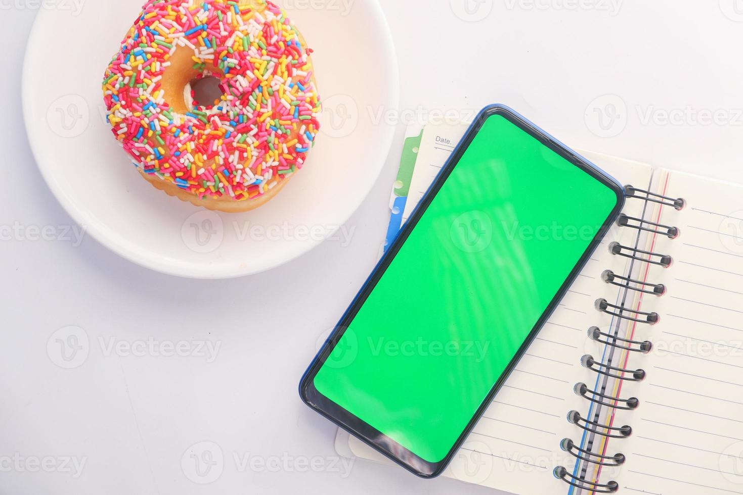 Donut und Green Screen Smartphone auf dem Schreibtisch foto