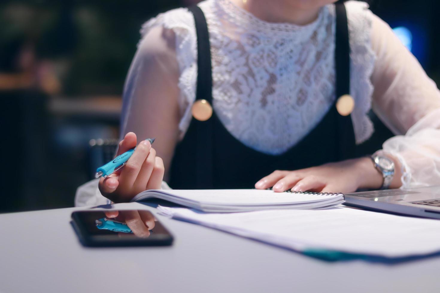 Frau, die Notizen an einem Schreibtisch schreibt foto