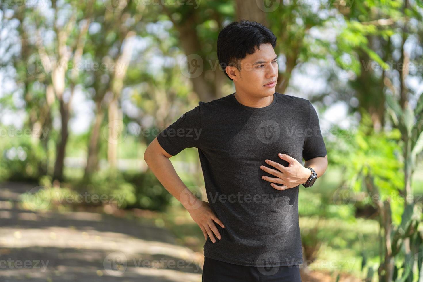 männlich asiatisch Athlet hat Truhe Schmerzen Fitness während Laufen im das Park foto